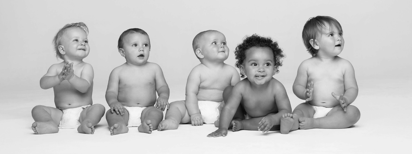 A group of babies, appearing to be happy and interested to the surroundings of the room.